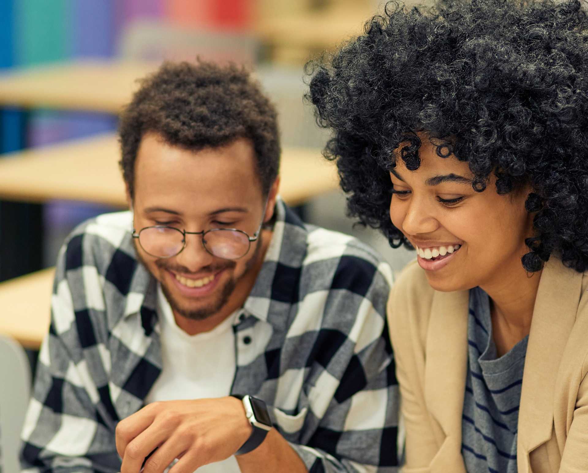 Two young employees (of multicultural multifaith b/grounds) looking at a laptop